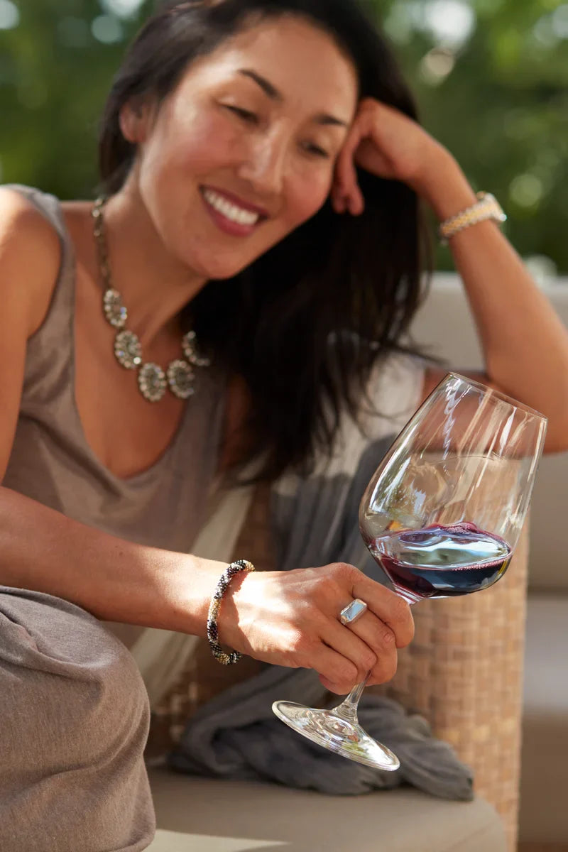 Woman smiling while holding a glass of 2020 HALL Eighteen Seventy-Three Cabernet Sauvignon
